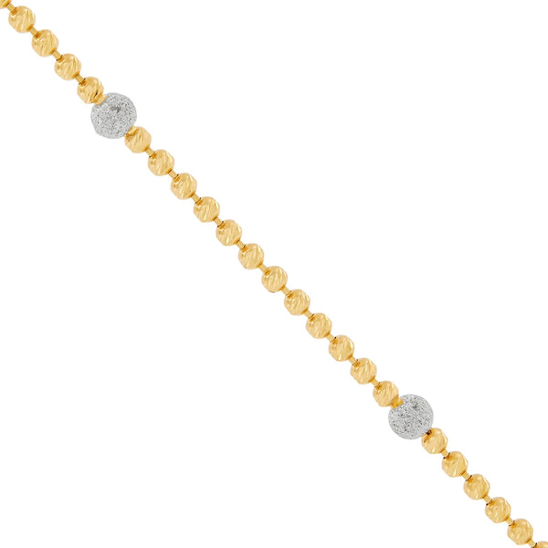 Close-up of a gold bead chain with two sparkling white beads