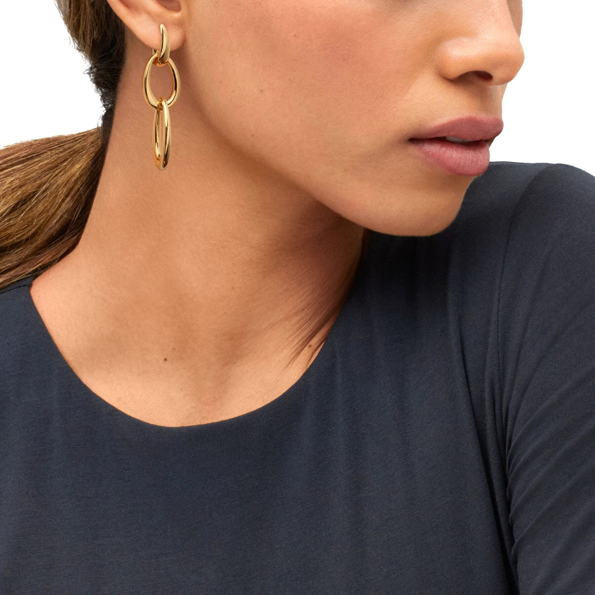 Profile of a model in a navy top wearing gold double oval-link drop earrings